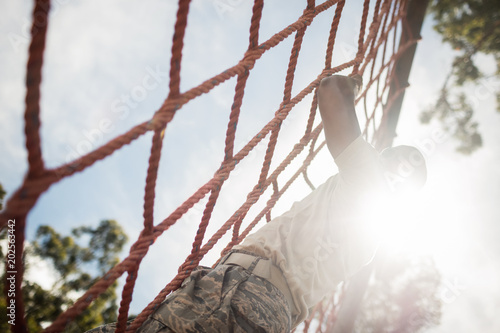 Military soldier climbing rope during obstacle course photo