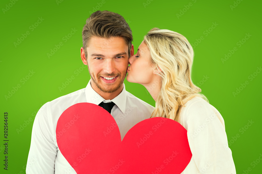 Attractive young couple holding red heart against green vignette