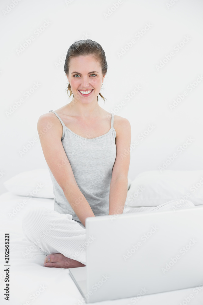 Portrait of a smiling casual woman with laptop in bed Portrait of a smiling casual woman with laptop in bed