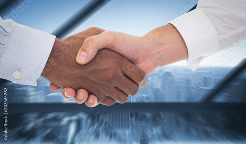 Close-up shot of a handshake in office against room with large window looking on city