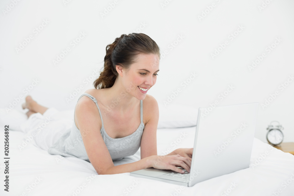 Smiling casual woman using laptop in bed Smiling casual woman using laptop in bed