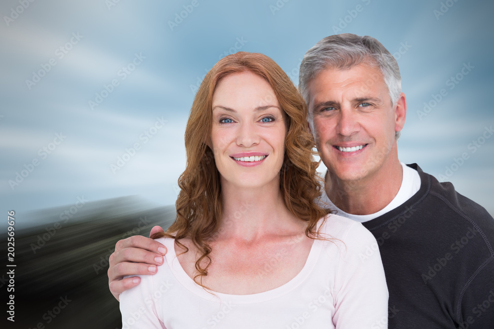 Casual couple smiling at camera against large rock overlooking big city