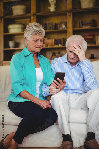 Tense senior couple looking at mobile phone