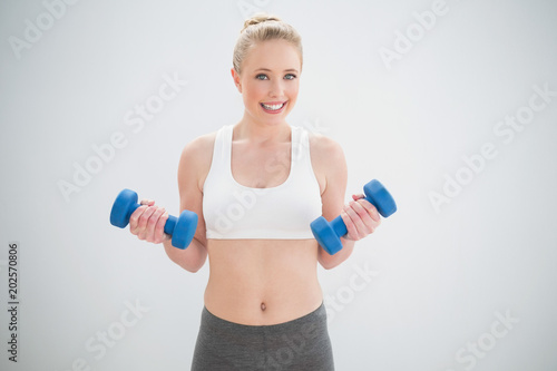 Smiling sporty blonde holding dumbbells