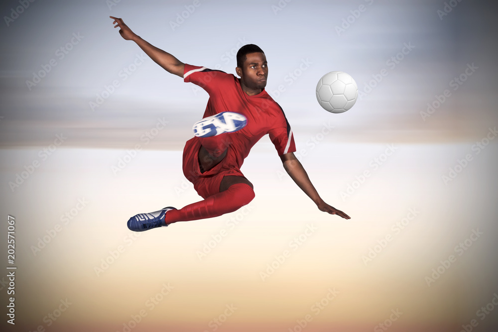 Football player in red kicking against beautiful orange and blue sky Football player in red kicking against beautiful orange and blue sky