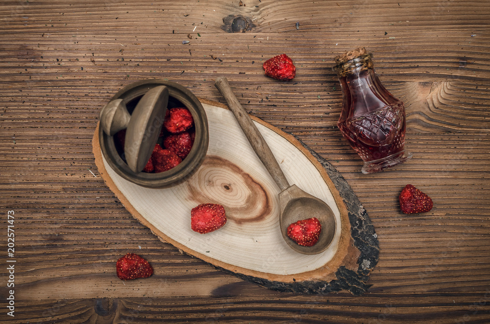 Herbal medicine concept. Dry strawberry in the jar and strawberry essential oil on wooden brown table. Organic ingredients. Herbal medicine concept. Dry strawberry in the jar and strawberry essential oil on wooden brown table. Organic ingredients.