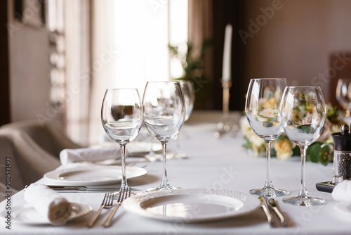Table setting in the restaurant  glasses in the foreground. Luxury wedding reception. Flower arrangement on table in restaurant. Stylish decor and adorning.