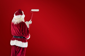 Composite image of father christmas paints a wall against red background