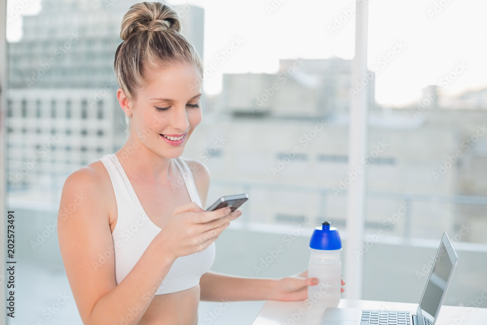 Laughing sporty blonde sending a text Laughing sporty blonde sending a text