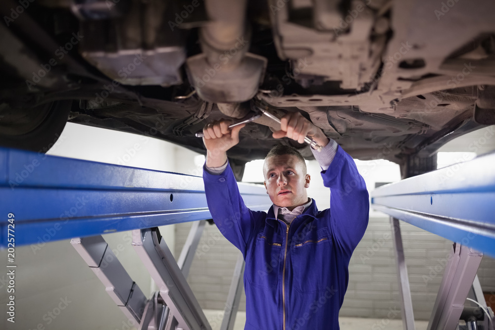 Concentrated mechanic repairing a car with tools Concentrated mechanic repairing a car with tools