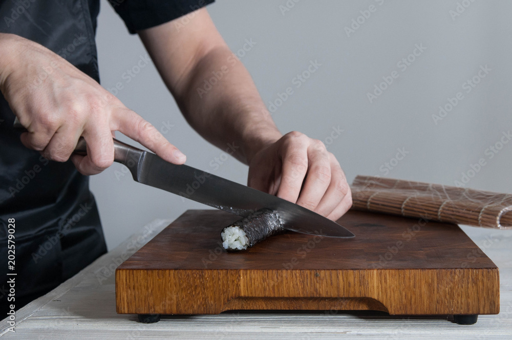 Process of making maki sushi. Cook chef hands preparing rolls with cheese, avocado, salmon and sesame seeds on wooden board Process of making maki sushi. Cook chef hands preparing rolls with cheese, avocado, salmon and sesame seeds on wooden board