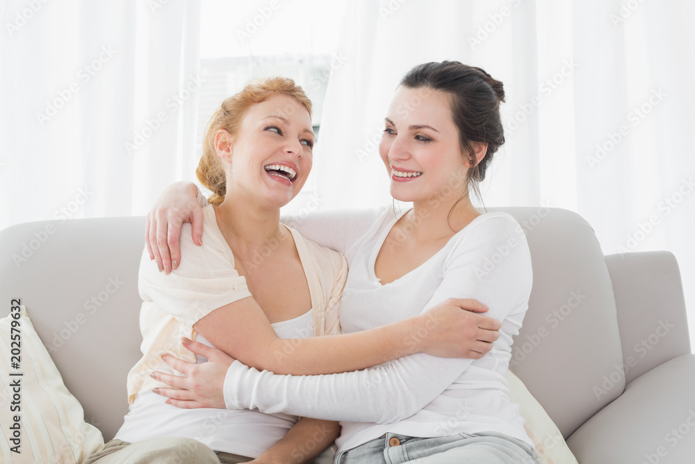 Cheerful female friends embracing in living room Cheerful female friends embracing in living room