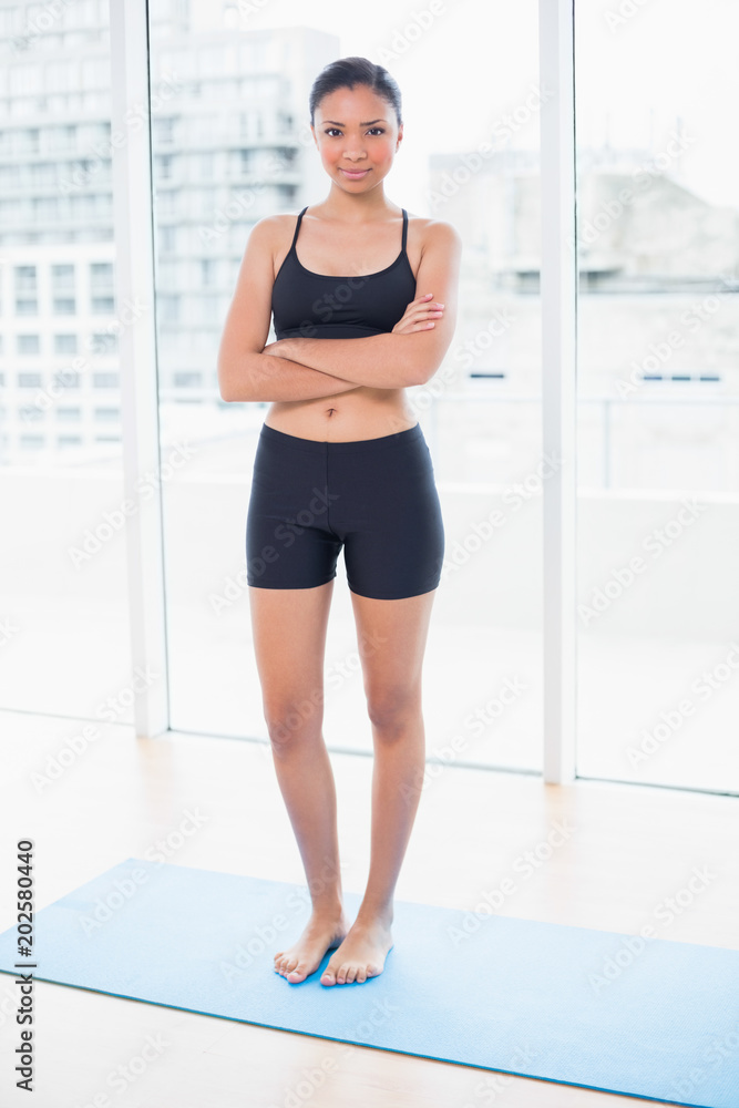 Pleased dark haired model in sportswear posing with crossed arms Pleased dark haired model in sportswear posing with crossed arms