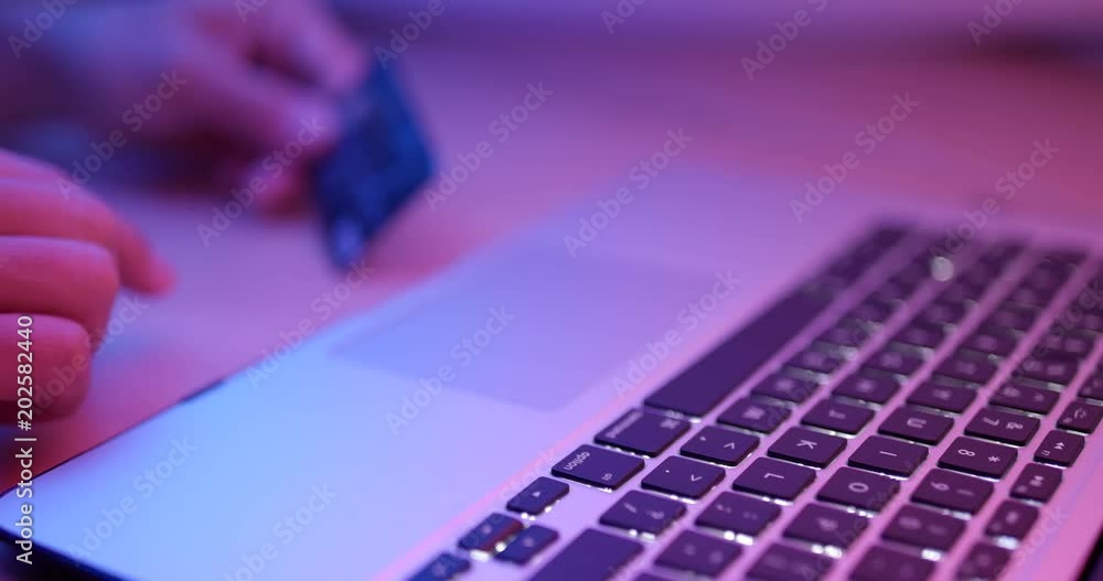 Typing on keyboard of computer for online shopping at night with red and blue light Typing on keyboard of computer for online shopping at night with red and blue light