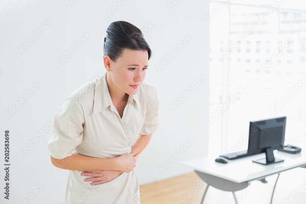 Businesswoman with stomach pain in office
