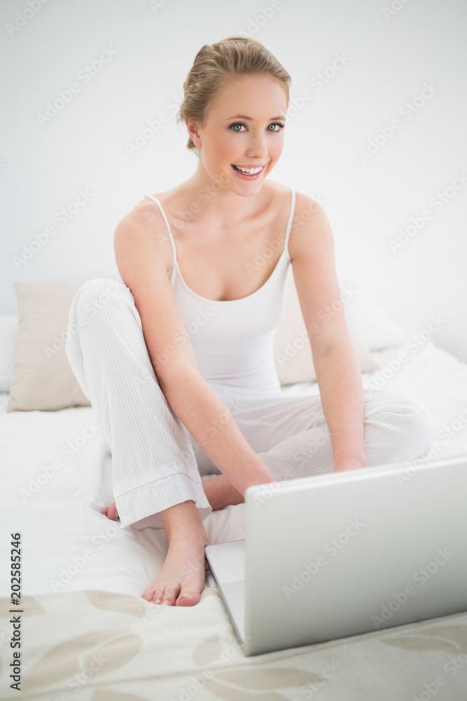 Natural happy blonde sitting in front of laptop on bed Natural happy blonde sitting in front of laptop on bed