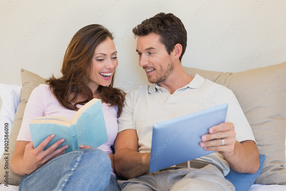 Happy couple with laptop and book on couch Happy couple with laptop and book on couch
