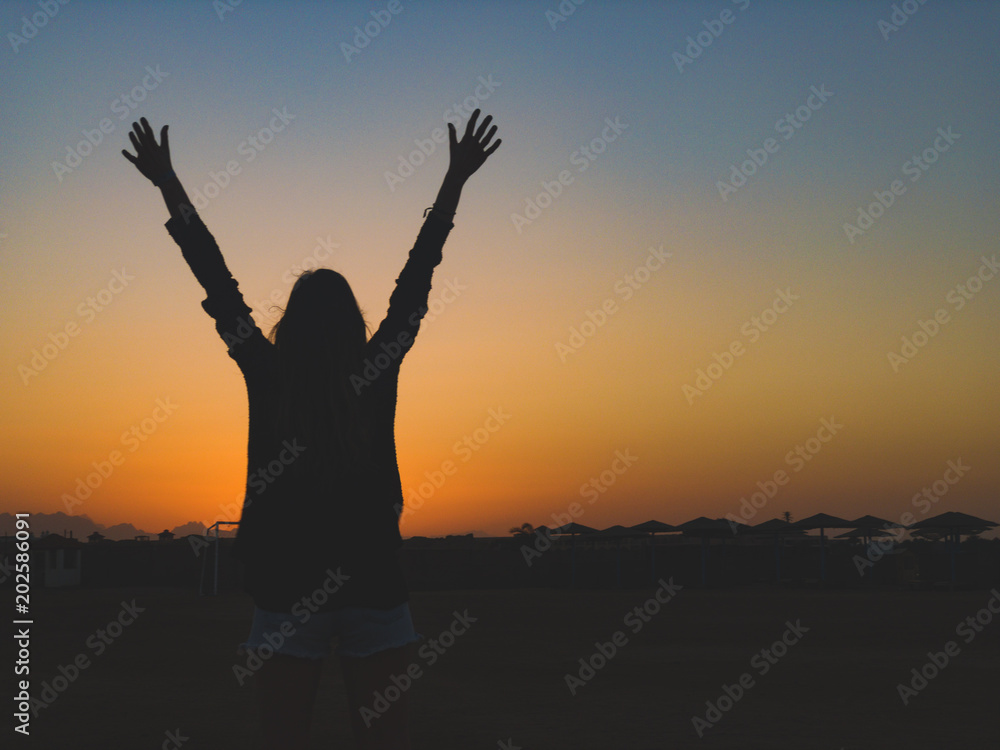 Silhouette of a girl with arms wide open in sunrise / sunset time.