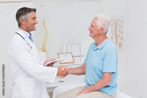 Male doctor and senior patient shaking hands