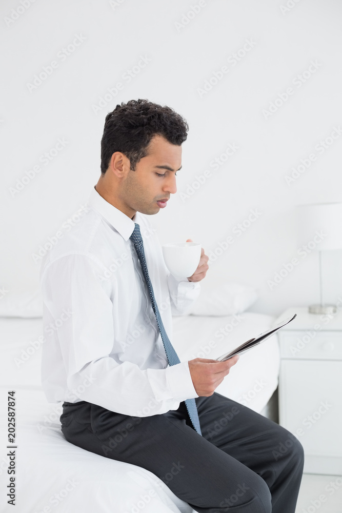 Businessman with cup reading newspaper at hotel room