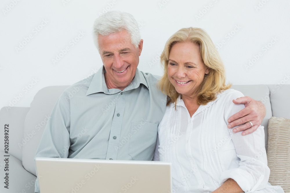 Relaxed senior couple using laptop at home Relaxed senior couple using laptop at home