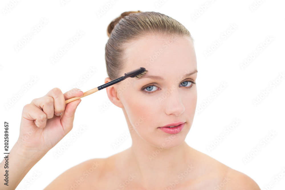 Natural pretty blonde model using an eyebrow brush