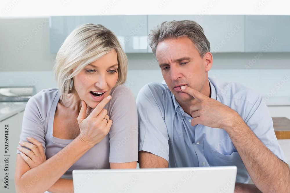 Couple using laptop in the kitchen Couple using laptop in the kitchen