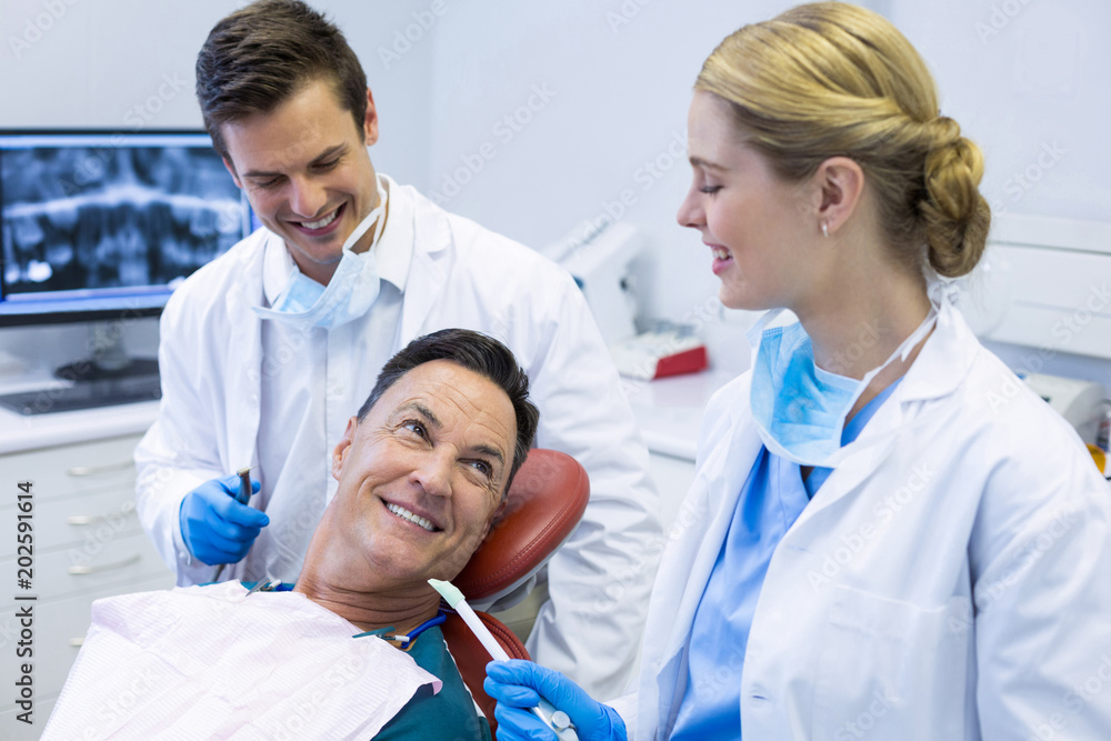Dentists interacting with a male patient Dentists interacting with a male patient