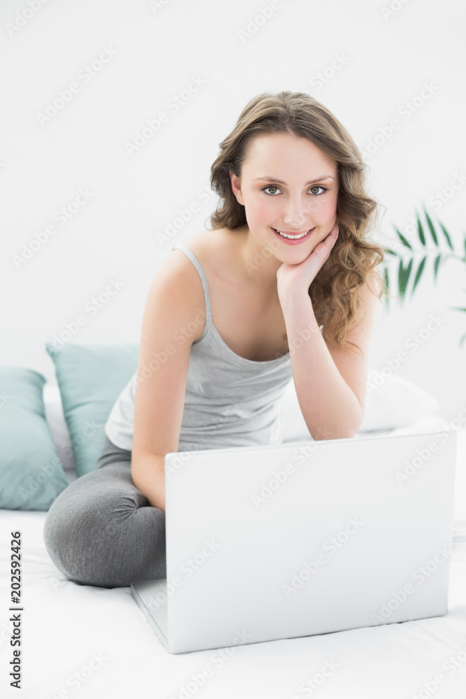 Smiling casual brunette using laptop in bed Smiling casual brunette using laptop in bed