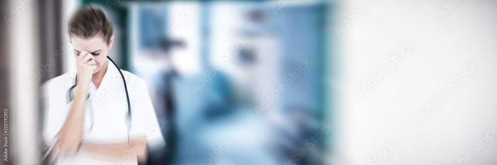 Female doctor suffering from headache against empty corridor in a hospital Female doctor suffering from headache against empty corridor in a hospital