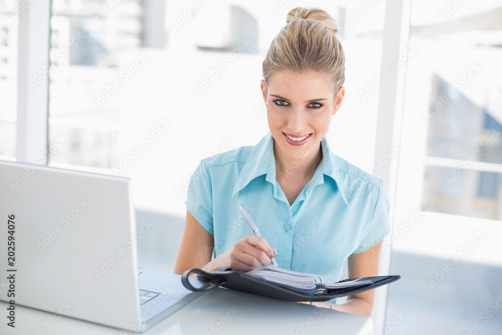 Cheerful well dressed businesswoman writing on datebook Cheerful well dressed businesswoman writing on datebook