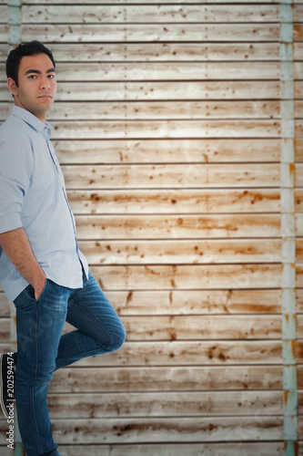 Unsmiling casual man standing against wooden background in pale wood
