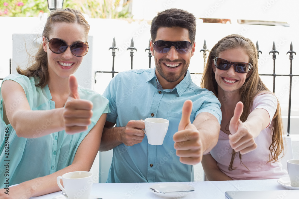 Happy friends gesturing thumbs up in café Happy friends gesturing thumbs up in café
