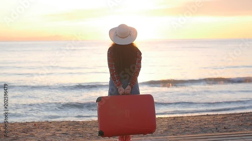 Young woman walking with a suitcase on the beach photo