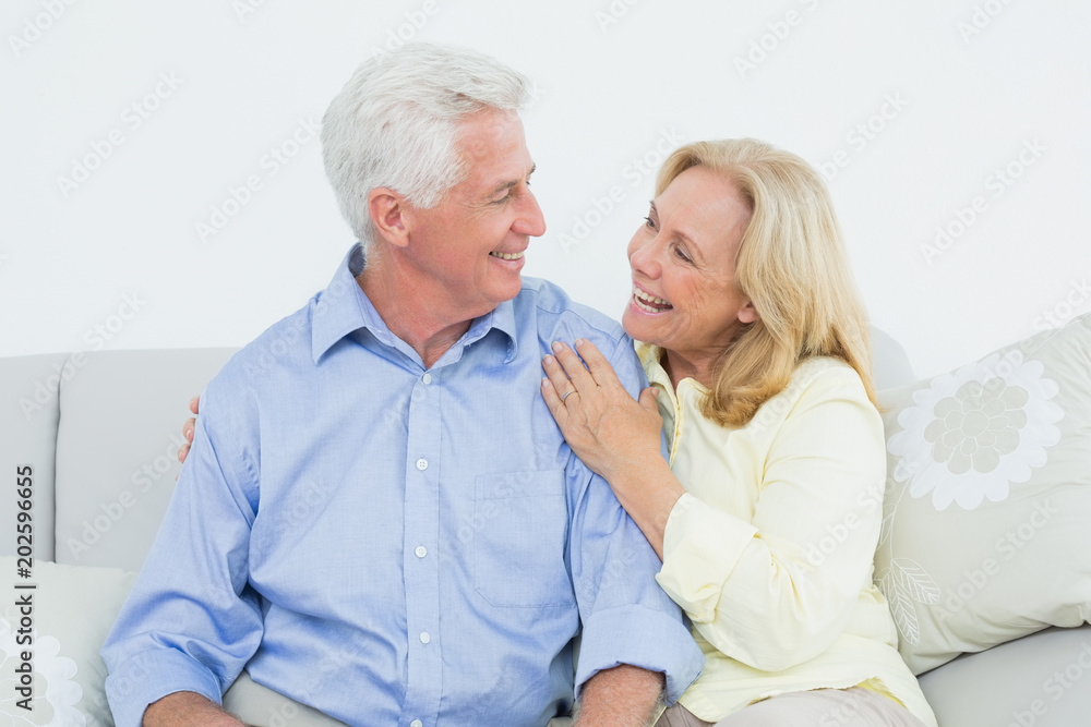 Cheerful loving senior couple sitting on sofa Cheerful loving senior couple sitting on sofa