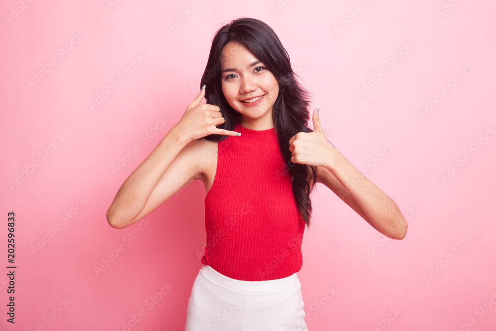 Young Asian woman thumbs up show with phone gesture. Young Asian woman thumbs up show with phone gesture.