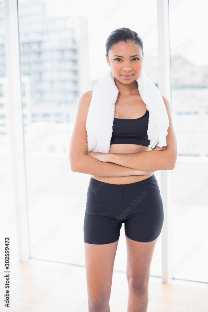 Confident dark haired model in sportswear posing with arms crossed