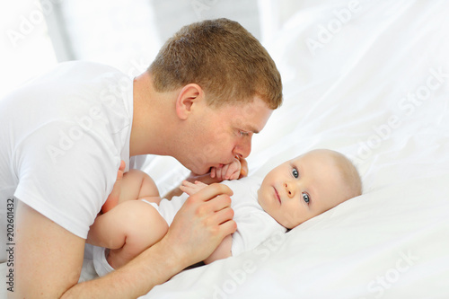 Family portrait of daddy and baby in white bed. The concept of family.