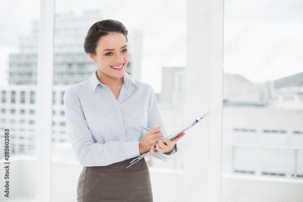 Smiling elegant businesswoman with clipboard in office Smiling elegant businesswoman with clipboard in office