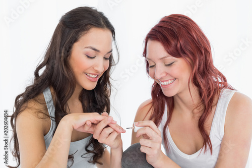 Smiling pretty young woman painting friends nails