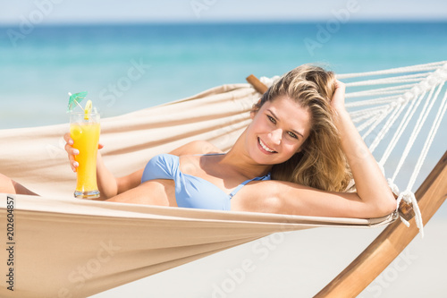 Pretty woman holding cocktail in the hammock 