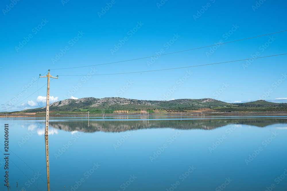 Landscape of a hill, lake and clouds with a light post