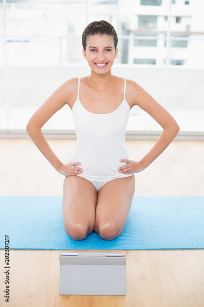 Cute natural brown haired woman in white sportswear posing with hands on the hips Cute natural brown haired woman in white sportswear posing with hands on the hips