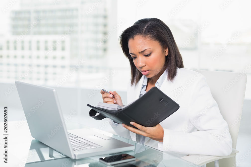Anxious young dark haired businesswoman filling her schedule Anxious young dark haired businesswoman filling her schedule