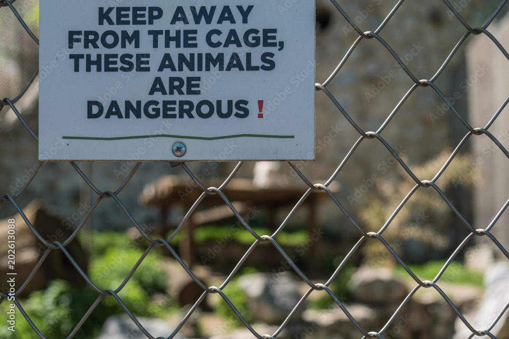 Warning sign on dangerous animal cage in a zoo Warning sign on dangerous animal cage in a zoo