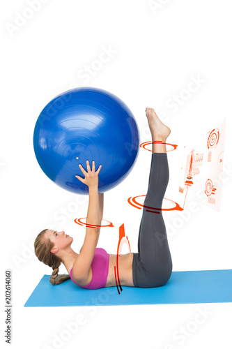 Side view of a fit woman exercising with fitness ball against fitness interface