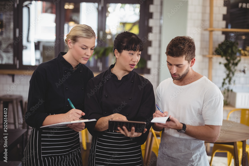 Young waiter and waitress discussing over digital tablet Young waiter and waitress discussing over digital tablet