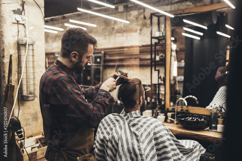 Hipster young good looking man visiting hairstylist in barber shop.