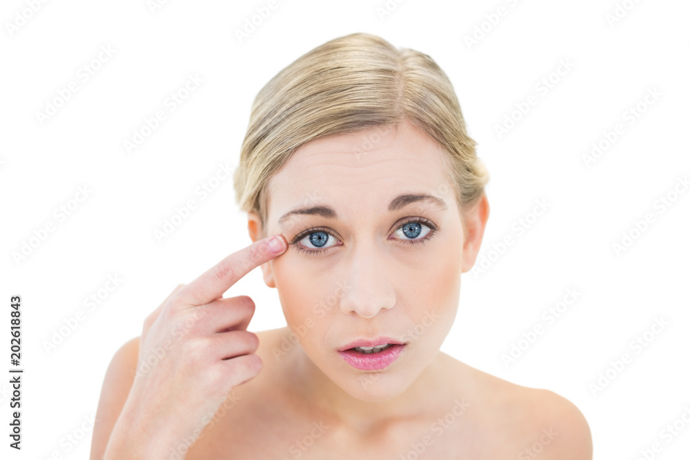 Anxious young blonde woman pointing her eye with her finger