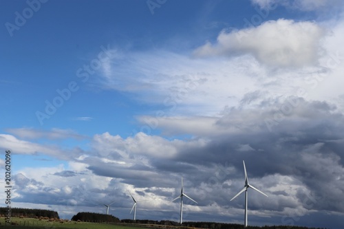 Wind tturbines against blue sky with fluffy white clouds